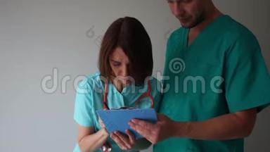 女医生在年轻实习生手中的文件夹中签名。 医生和实习生，医疗助理